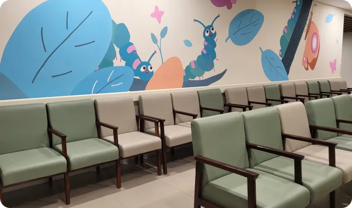 Waiting area with green chairs and mural at Kauvery Hospital